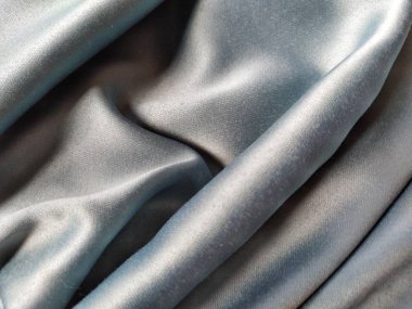 İpeksi, parlak bir ışıltıyla gri-mavi dokuya dokunuyor. Doğal ışıklandırma, ışık ve gölge. Malzeme gelişigüzel katlanmış. Polyester Tekstil