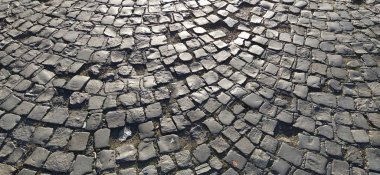 Eski asfalt. Gri taşlardan yapılmış kaldırım. Eski şehrin meydanındaki kaldırım taşları. Olaysız fayanslar daire çiziyor. Doğal taş dokusu