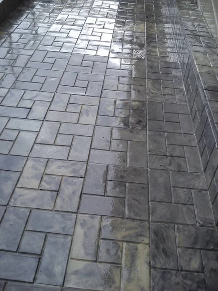 binadan gölge ile yağmur dan sonra kaldırımda ıslak gri kiremit.