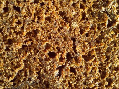 Kahverengi çavdar ekmeği yakın plan. Vitaminli, mineralli, kepekli ve tohumlu sağlıklı yiyecekler. Yüksek kaliteli fırın ürünü. Gevşek, gözenekli ve delikli..