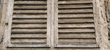 Penceredeki eski ahşap panjurlar. Antika ahşap mimari. Rengi solmuş hışırtılı kuru ahşap. Kabuk ve toz. Doğal renk. Pencere pervazı, yatay çizgiler ve kirişler