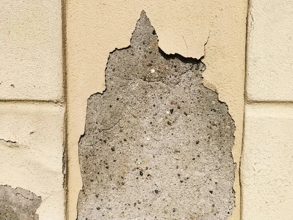 Plaster falling off the wall of a building. Facade condition in need of repair.