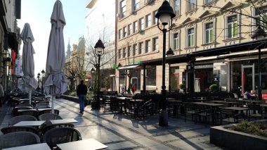 Belgrad, Sırbistan - 24 Ocak 2020: Şehir merkezinde sabah caddesi. İnsanlar işlerini aceleye getiriyorlar. Sokak kafeleri hâlâ kapalı. Masalar, sandalyeler ve şemsiyeler. Yoldan geçenler gitsin..