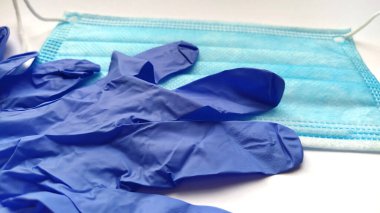 COVID-19. Coronavirus. Tıbbi lateks eldivenler ve beyaz arka planda koruyucu mavi cerrahi maske. Biyolojik tehlike koruması. Yakın plan. Test kiti. Tıbbi bir temanın resmi ya da arkaplanı. Mavi ince eldiven.