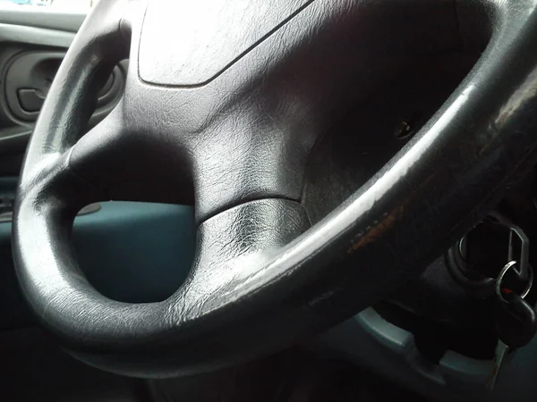 Vehicle interior. Dark steering wheel. The interior of the car cab. Dark upholstery. Vehicle keys in the contact slot. Round steering wheel.
