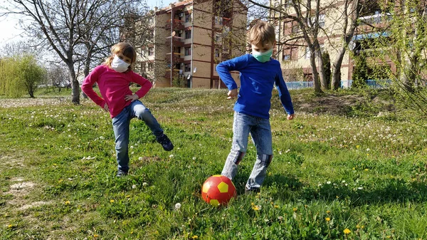 Мальчик Девочка Защитных Хирургических Масках Играют Мяч Танцуют Зеленой Траве — стоковое фото
