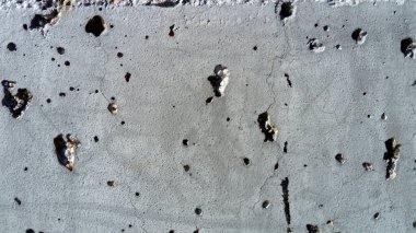 Büyük çaplı konsantrasyon hasarı olan beton duvar. Çukurlar, tüberkülozlar ve kusurlar. Gri renk. Gezegen yüzeyi. Çürük yüzeyi, çukurları, çıkıntıları ve küçük lekeleri olan beton bir duvar.