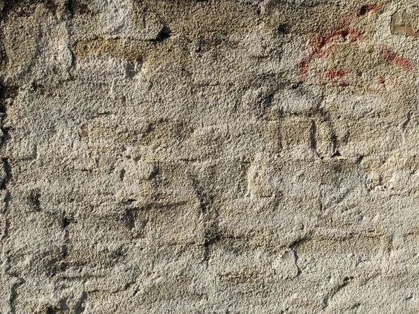 Old brick wall covered with a thin layer of plaster. Uneven surface. Texture background.