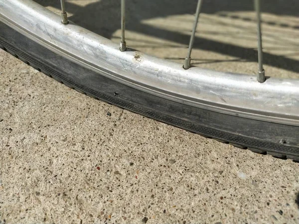 Flat tire on a bicycle. Wheel flattened on asphalt. The hole in the rubber tire. Aluminum Bicycle Wheel Frame.