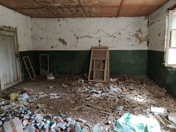 Внутри заброшенного дома. Гранж-сцена. Разбросанный мусор на полу. Зеленая краска на стенах. Белая половина стены. Выстрел деревянных оконных рам. Остались бутылки, листочки бумаги и другие предметы
.