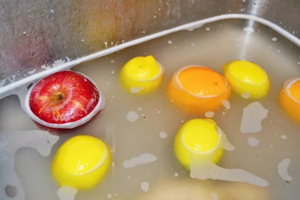 Elma, limon ve portakallar lavaboda deterjan ile sabunlu suda yüzüyor.