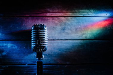 Retro microphone on wooden background and lights clipart
