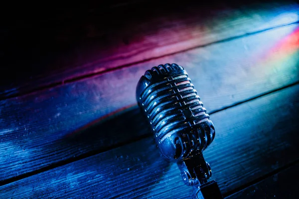 Retro microphone on wooden background and lights — Stock Photo, Image