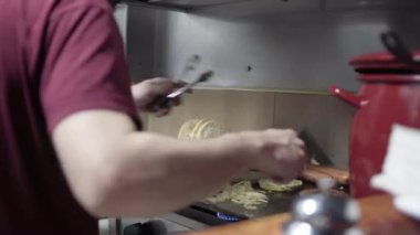 Şef sıcak tabakta bir burger hazırlıyor.