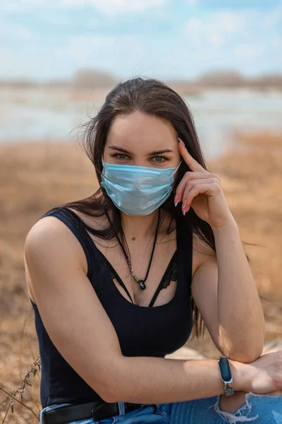 Salgına karşı savaşan genç bir kız tıbbi bir maske taktı.