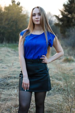 Ormanda otların arasında duran şık bir kızın portresi. Büyüleyici mavi gözler. Onun uzun sarı saçları omuzlarının üzerine düzgünce düşer. Modaya uygun mavi bluz ve siyah deri etek..