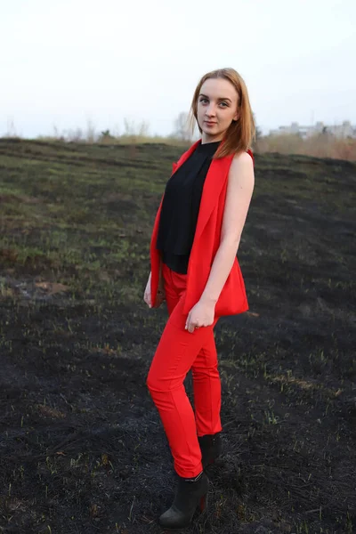 Ein Mädchen Roten Anzug Vor Dem Hintergrund Eines Verbrannten Feldes — Stockfoto