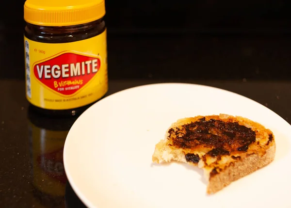 Sydney, Australie - Le 2 novembre 2019 - Vegemite et beurre sur du pain grillé à la pâte à soupe avec morsure en arrière-plan avec pot Vegemite. Une icône classique propagation australienne . — Photo