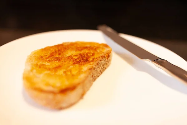 Pâte à soupe blanche pain grillé au beurre avec couteau argenté sur plaque blanche et plan de travail en granit noir — Photo