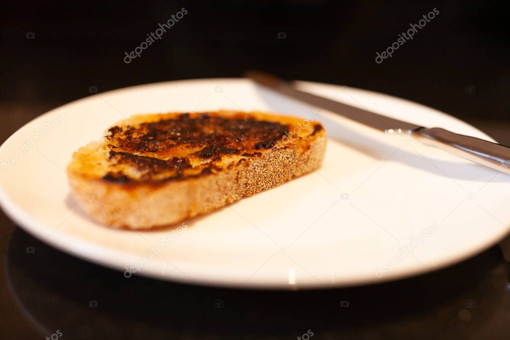 Vegemite and butter on sough dough toast with knife on Kitchen bench. An classic icon Australian spread. 