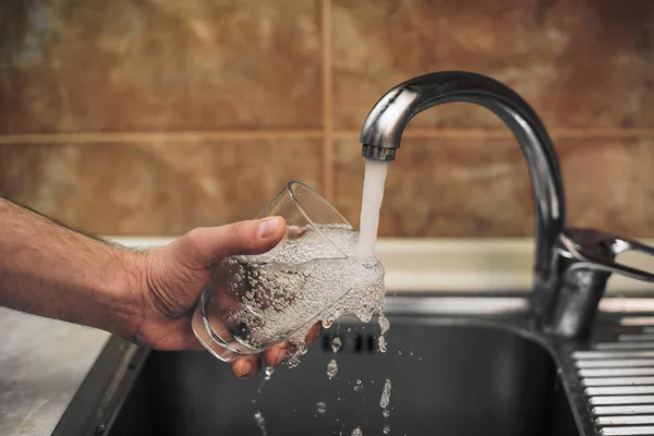 Man pours glass of water from the tap — Stock Photo, Image