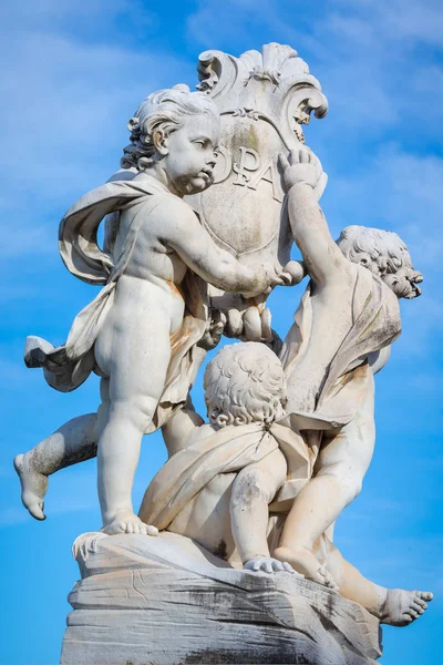 Statue of cherubs holding a shield with the Cross of Pisa on it in Pisa, Italy — Stock Photo, Image