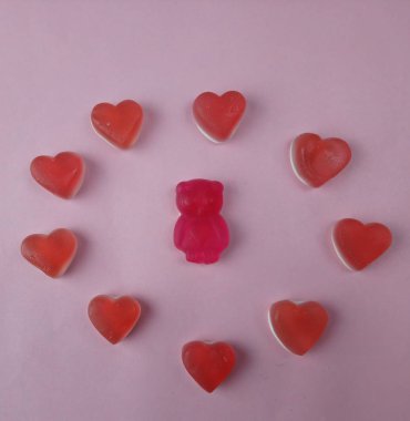 Kırmızı kalpler ve marmelattan yapılmış bir ayı masada yatıyor.