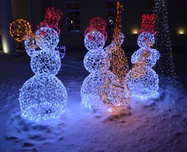 Üç güzel kardan adam müzisyen karın üzerinde duruyor.