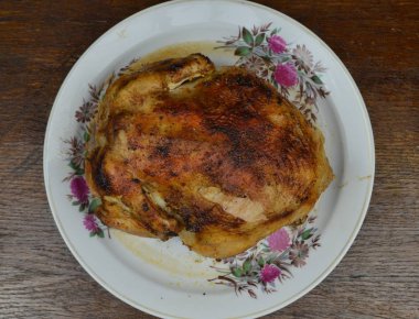 Fırında pişmiş tavuk tabakta yatıyor.