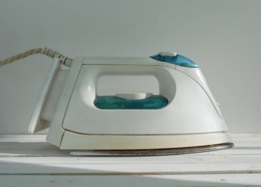 Beyaz plastik ütü masanın üzerinde duruyor.