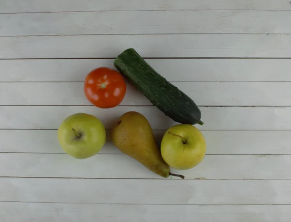 cucumber, pear, two apples and a tomato are on the table