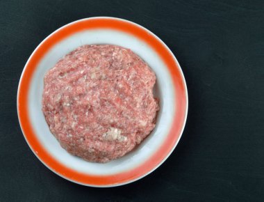 kıyma siyah arka planda bir tabakta yatıyor.