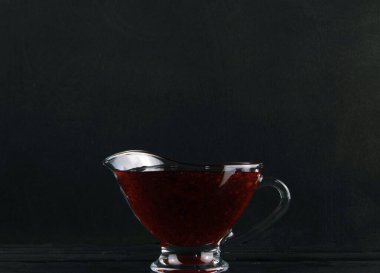 Çilek reçelli kupa ahşap bir masada duruyor.