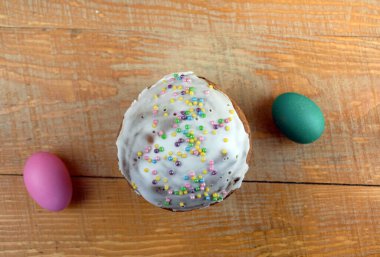 Tatil pastası ve renkli yumurtalar ahşap bir masada yatıyor.