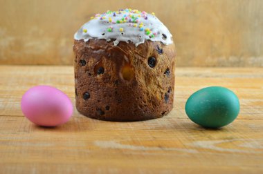 İki renkli yumurta ve Paskalya pastası ahşap bir masada yatıyor.