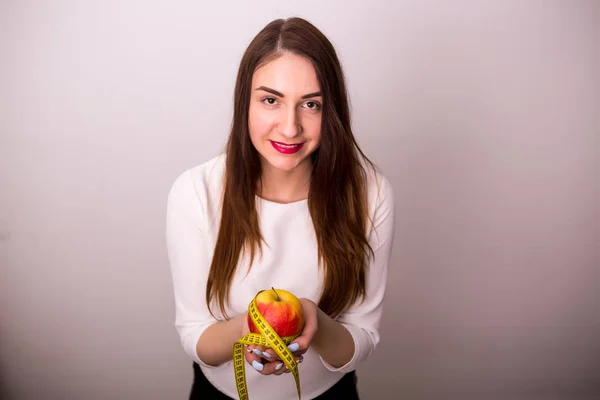 Kvinnlig hand håller ett äpple och måttband — Stockfoto