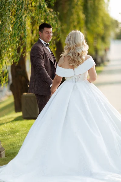 Full length body portrait of young bride and groom running on green grass of golf course, back view. Happy wedding couple walking through golf course, copy space — 스톡 사진
