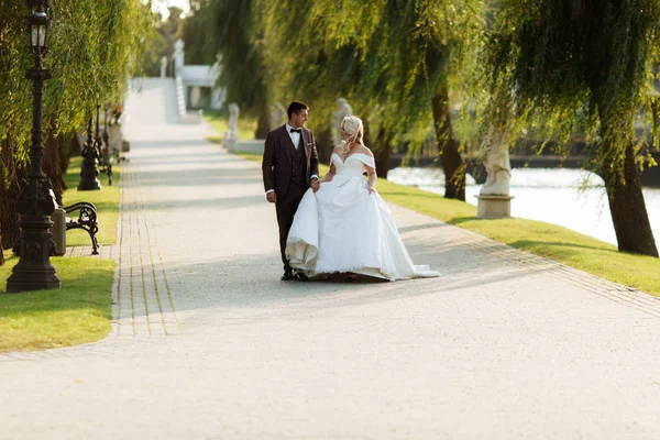 Retrato de cuerpo entero de novia joven y novio corriendo sobre hierba verde del campo de golf, vista trasera. Feliz pareja de boda caminando por el campo de golf, espacio para copiar — Foto de Stock