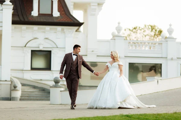 Retrato de cuerpo entero de novia joven y novio corriendo sobre hierba verde del campo de golf, vista trasera. Feliz pareja de boda caminando por el campo de golf, espacio para copiar — Foto de Stock