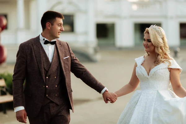 The bride and groom walk together in the park. Charming bride in a white dress, the groom is dressed in a dark elegant suit — 스톡 사진