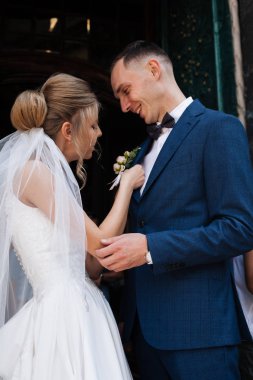 Takım elbiseli damat kravatını düzeltiyor. Ceketinin yakasında yaka çiçeği vardı. Takım elbiseli genç adam.