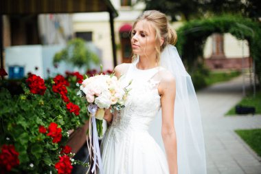 Şehirde beyaz elbiseli zarif bir gelin. Lüks makyajlı ve saç stili olan güzel bir gelin. Mutlu yeni evli kadın. Gülümseyen gelin. Düğün günü. Moda Gelini.