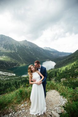 Güzel beyaz elbiseli gelin ve güzel yeşil dağlara bakan gelin ve mavi sulu göl