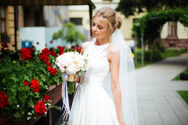 Νεαρή κομψή νύφη με λευκό φόρεμα στην πόλη. Όμορφη νύφη με πολυτελές μακιγιάζ και χτένισμα. Ευτυχισμένη νιόπαντρη γυναίκα. Χαμογελαστή νύφη. Την ημέρα του γάμου. Νύφη μόδας — Φωτογραφία Αρχείου