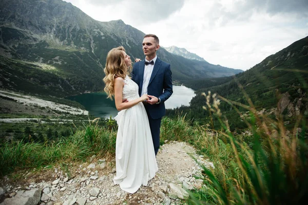 Sensuellt bröllopspar stående på den steniga stranden av sjön Sea Eye i Polen. — Stockfoto