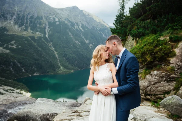 Glad brud och brudgum på deras bröllop. Brudgummen kysser brudens panna. Porträtt av bruden. Nygifta i parken. Ett lyckligt par. Bröllopsfoto. Par förälskade. — Stockfoto