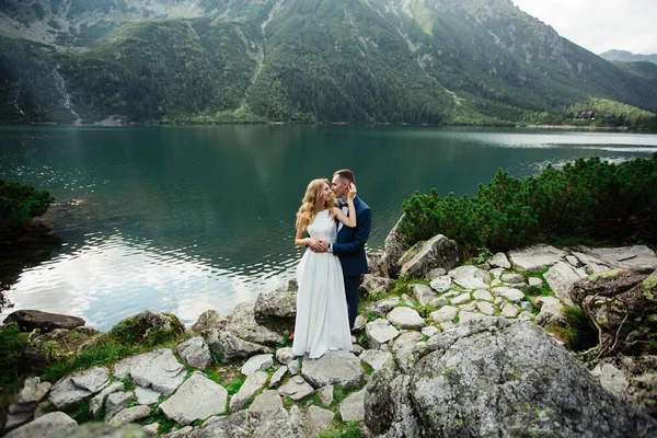 Sensuellt bröllopspar stående på den steniga stranden av sjön Sea Eye i Polen. — Stockfoto
