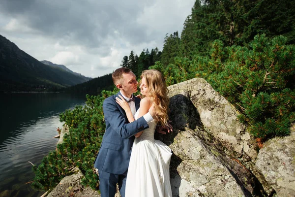 Couple de mariage sensuel debout sur la rive pierreuse du lac Sea Eye en Pologne . — Photo