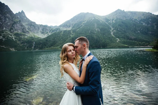 Sensuellt bröllopspar stående på den steniga stranden av sjön Sea Eye i Polen. — Stockfoto