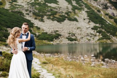 Güzel beyaz elbiseli gelin ve güzel yeşil dağlara bakan gelin ve mavi sulu göl